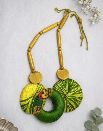 Nr. 2:Afro-Cuban necklace featuring green thread discs and wooden beads. Hand-wrapped elements and harmonious natural tones give this necklace a special depth and lightness. Discover exquisite craftsmanship